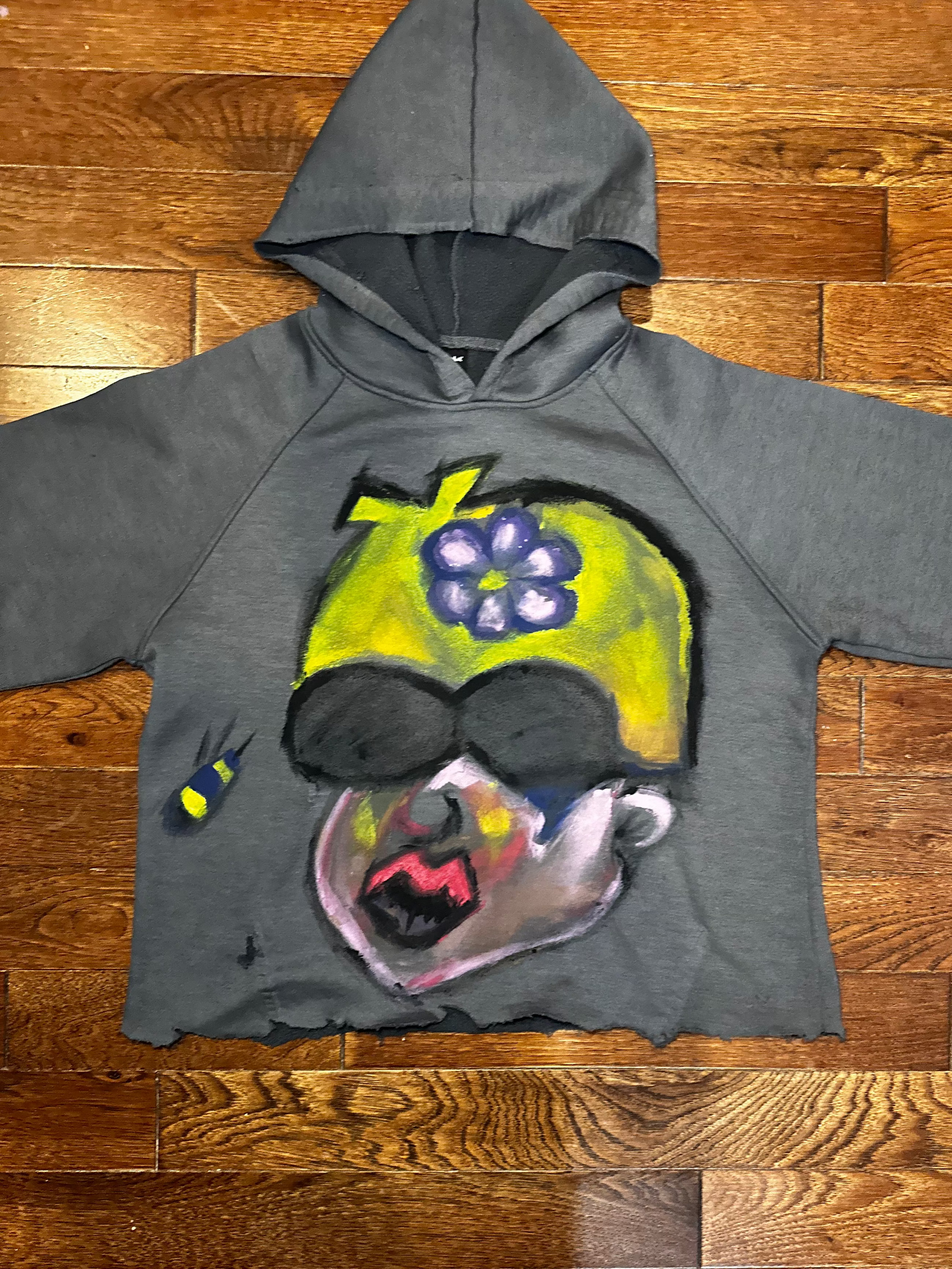 Gray hoodie with a colorful graphic design on a wooden floor